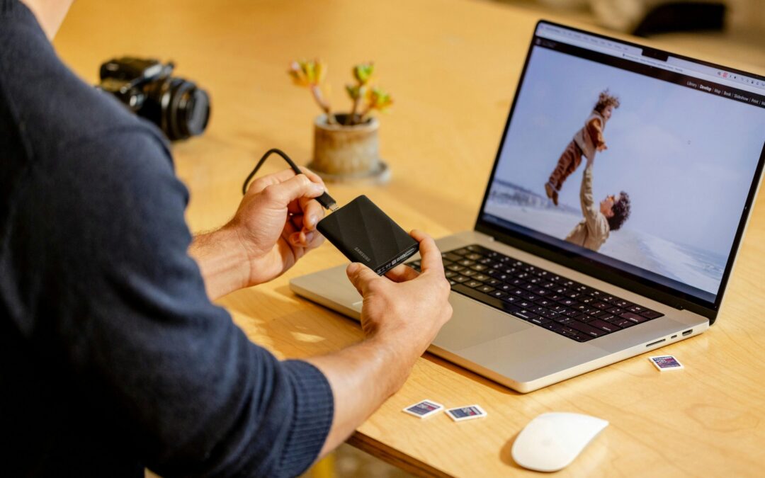 A man sitting at a table with a laptop and cell phone